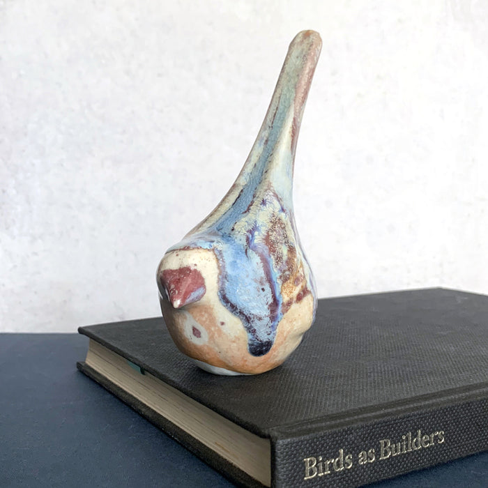 Small ceramic sculpture of a bird, glazed in a rust, cream and blue glaze by artist Becky Story. 