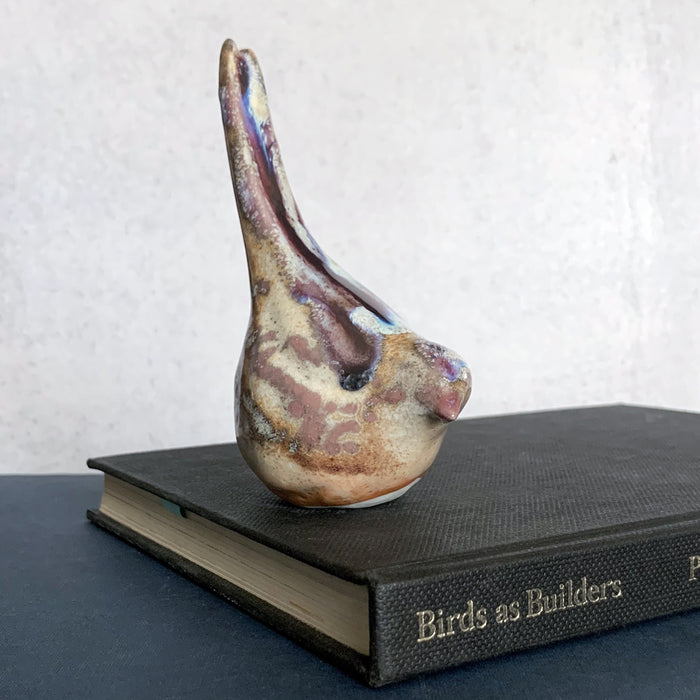 Small ceramic sculpture of a bird, glazed in a rust, cream and blue glaze by artist Becky Story. 