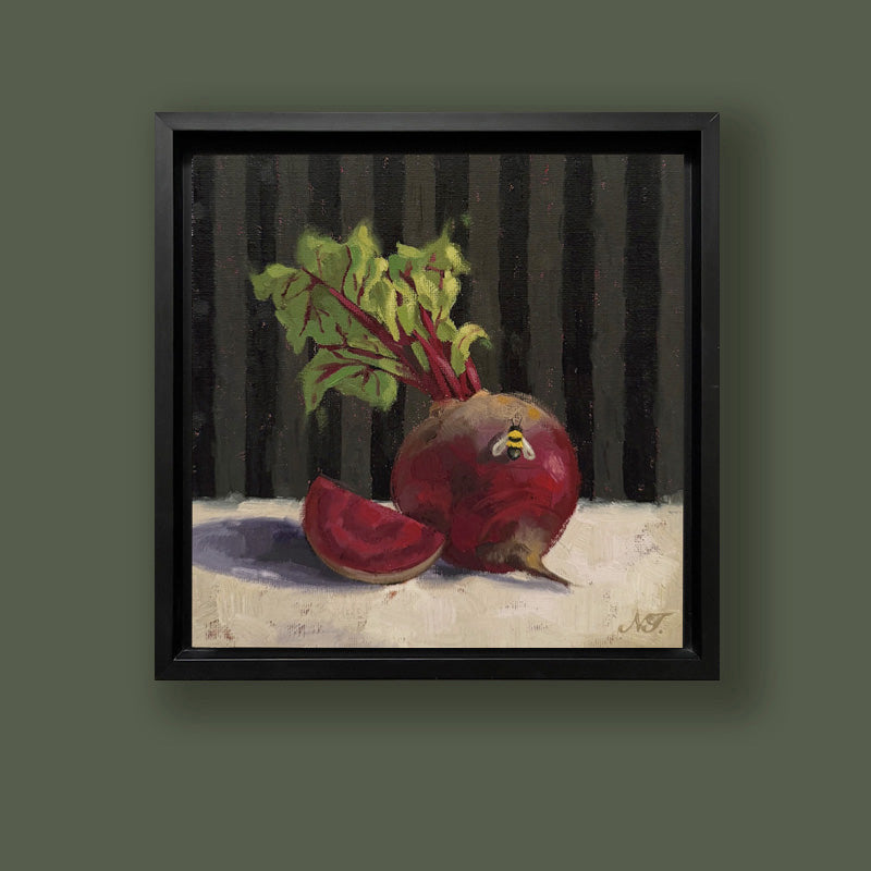 Bee and Beets, 8 x 8" hand painted rustic red beet and bee painting by Ninalee Irani. The oil painting is set in a black frame. Displayed on a green wall.