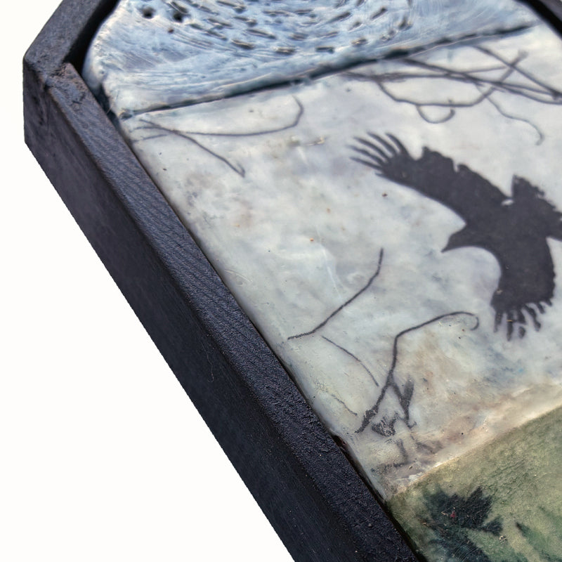 Small house shaped, mixed media encaustic artwork with fern, bird and moon imagery, set in black frame. Close up detail. 