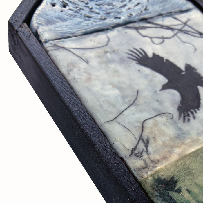 Small house shaped, mixed media encaustic artwork with fern, bird and moon imagery, set in black frame. Close up detail. 