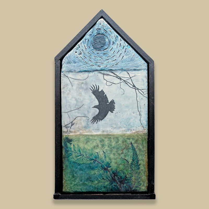 Small house shaped, mixed media encaustic artwork with fern, bird and moon imagery, set in black frame. Displayed on tan wall. 