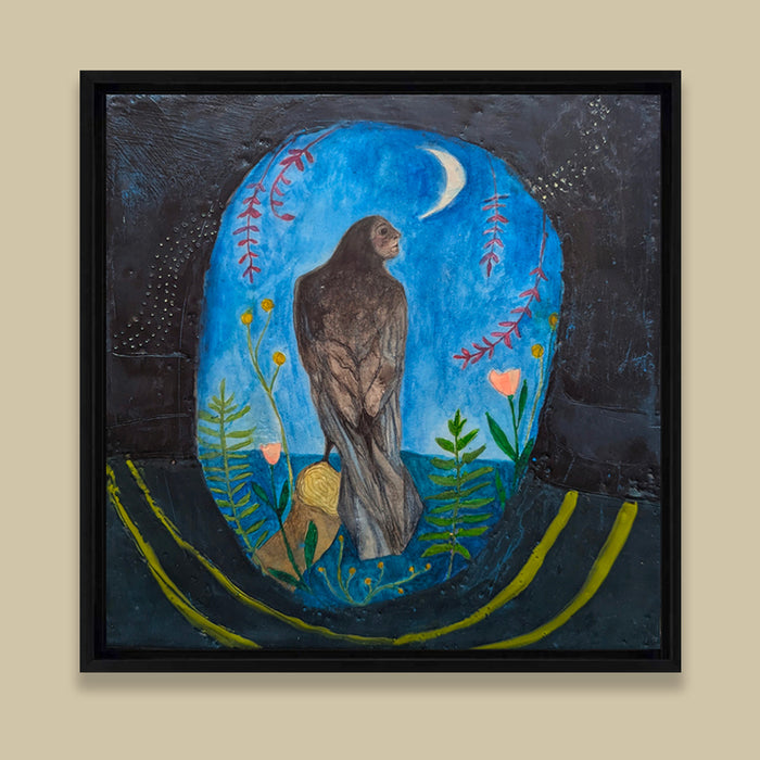 Framed mixed media encaustic painting featuring a mythical creature, a combination of raven and woman, perched on a branch under a night sky and crescent moon. She is surrounded by leaves, and pink and yellow flowers. Displayed on tan wall. 