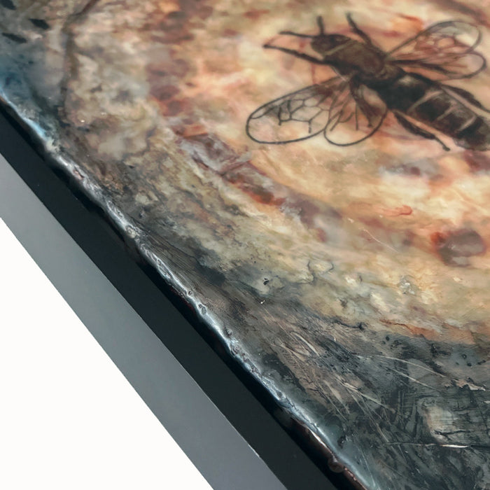 Mixed media artwork of a bee on a textured circular background, set in black frame. Close up detail.