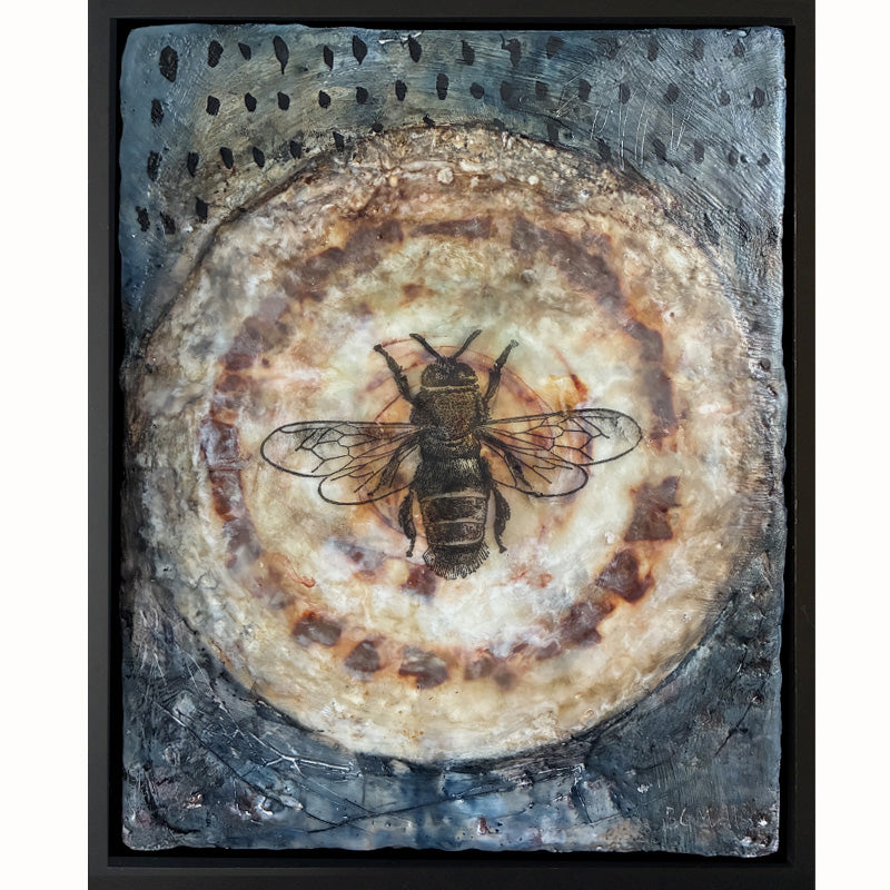 Mixed media artwork of a bee on a textured circular background, set in black frame.