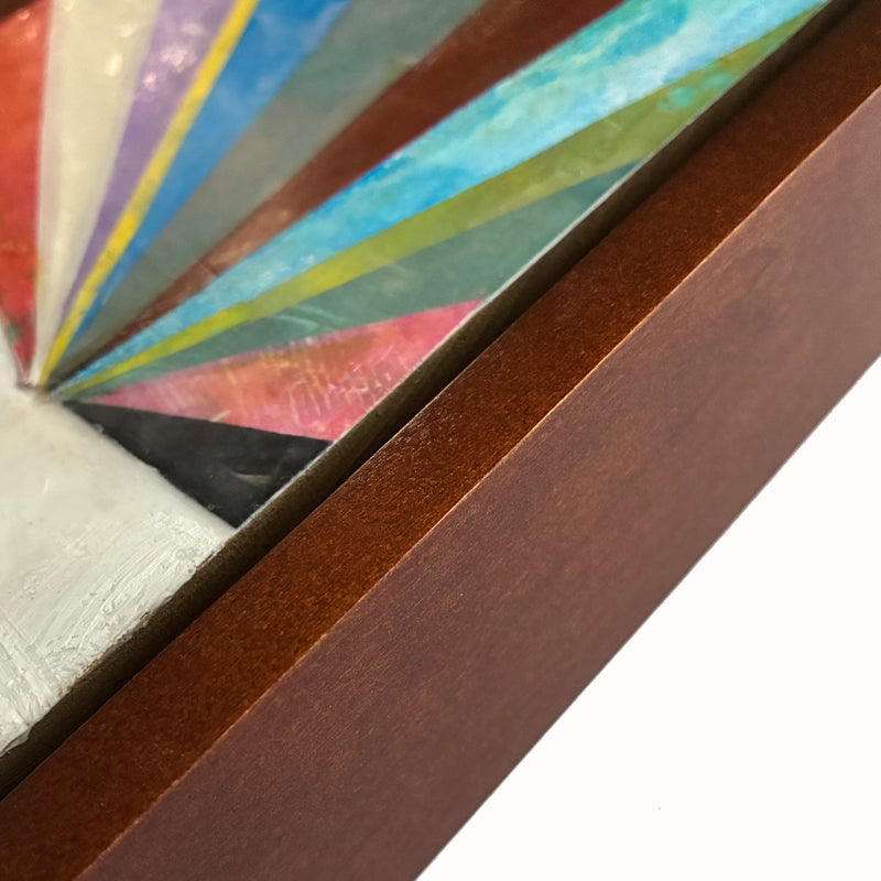 Artwork with colorful geometric design, and small bird in the top of a tree, set  in a wooden frame. Detail close up of frame.