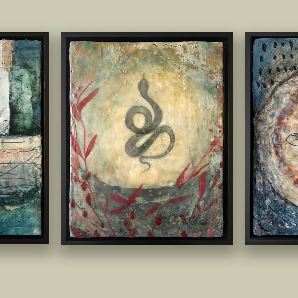Mixed media snake artwork on a beige wall along with two other paintings.