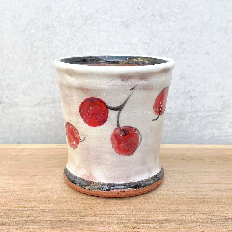 Handmade ceramic cup by NC potter Molly Lithgo. White with red cherry decoration. Alternate view.