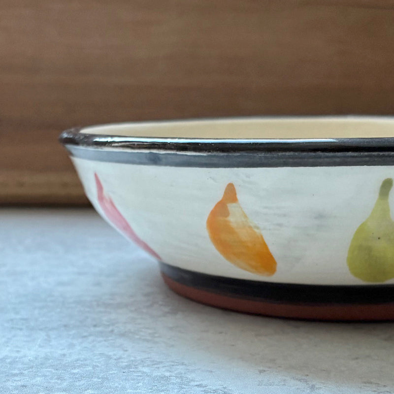 Handmade ceramic bowl with red, orange and green chili pepper decoration by Molly Lithgo. Side view.