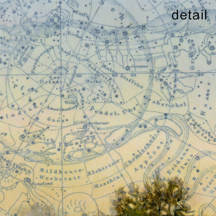 Detail of a small framed, mixed media landscape painting of a tree in a field beneath a celestial map sky.  Artwork by Christina Keith, matted and framed in black. 