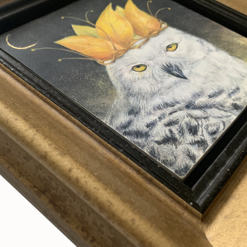 "Autumn Coronation" painting by Diane Savino. A snow owl wears a crown of golden leaves, with a sliver of the moon showing in a dark sky. The artwork is in a mottled gold frame, frame detail shown here.