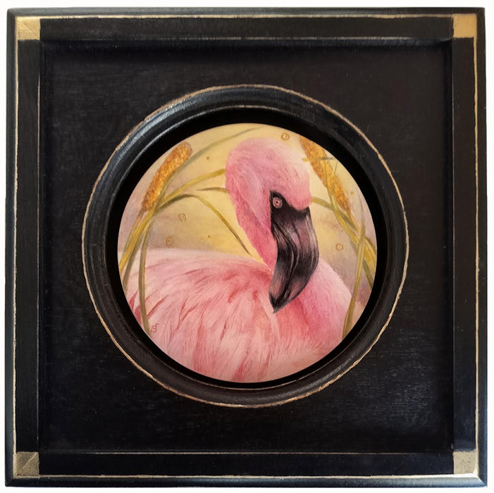 A 6" circular painting of a pink flamingo among yellow-green reeds set in a square black frame with gold leaf details.  Artwork by Diane Savino.