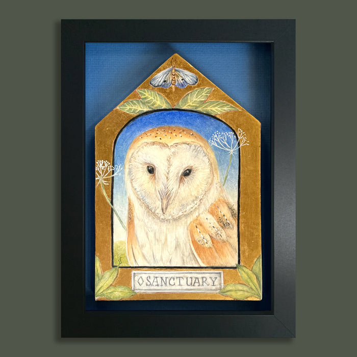 Sanctuary painting by Diane Savino, an owl sits inside a vignette on a house shaped form with foliage and a moth on top. Framed in black and shown on a dark green wall.