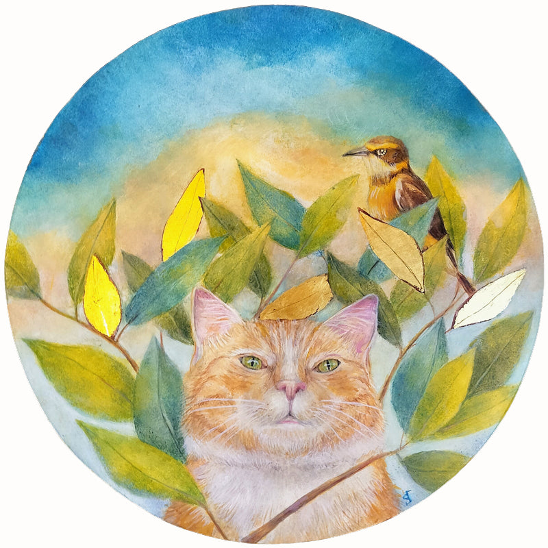A circular egg tempera and gold leaf painting featuring an orange cat looking through a cluster of green leaves, a small bird perched on a branch above, with a soft blue and yellow sky background. Original artwork by Diane Savino.