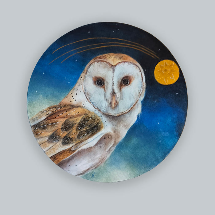 An 8" circular painting of a barn owl against a starry night sky with gold leaf details by Diane Savino. Shown on pale grey wall. 