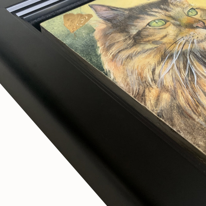 Under the Hunter Moon painting by Diane Savino, a cat sits under a golden moon and is surrounded by moths. Framed in black, detail shown.