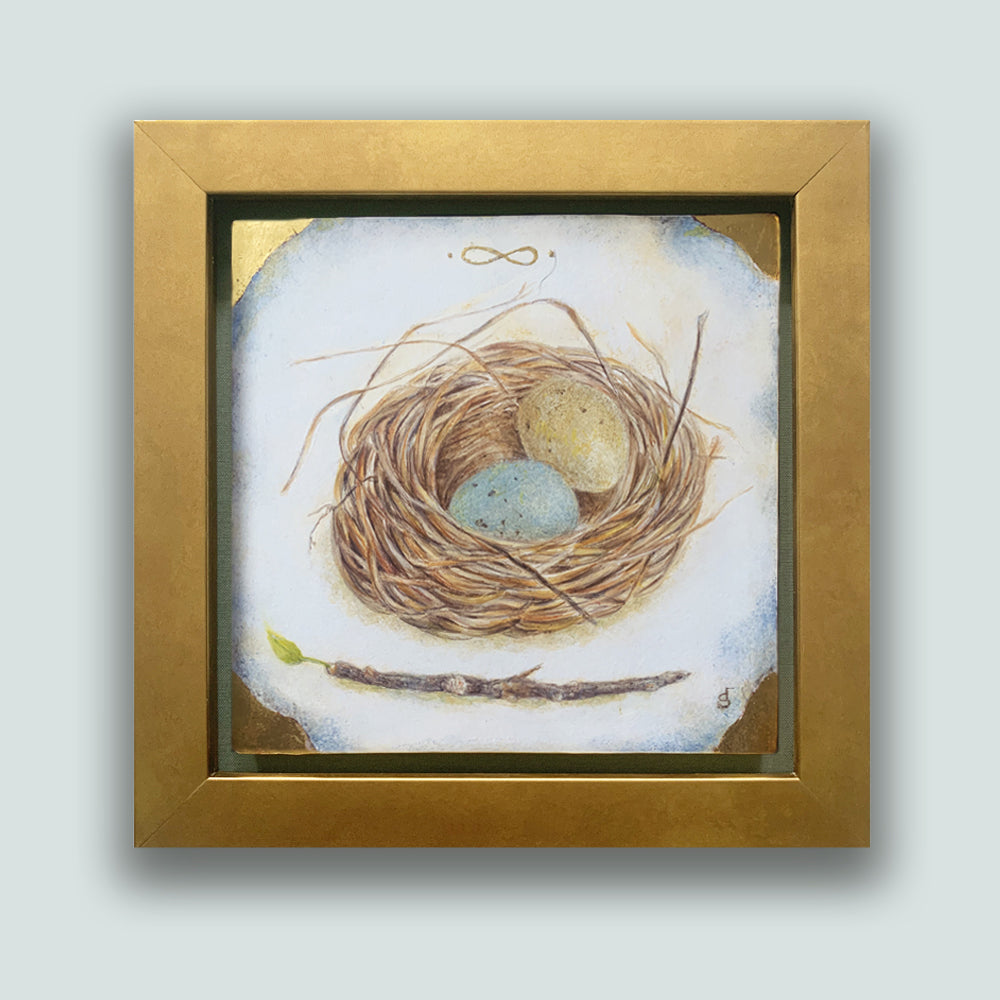 "With Promises to Keep" painting by Diane Savino. A nest holds one blue egg and one yellow egg, a small branch with a single green leaf below it. The artwork, set in a gold frame, is showcased on a pale blue wall.