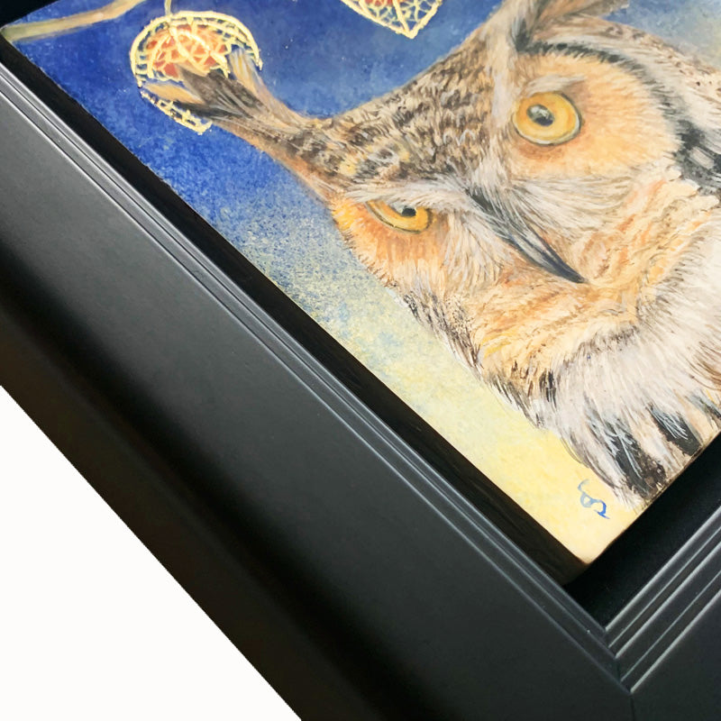 "Night's Awakening" painting by Diane Savino. A great horned owl sits under a brilliant blue night sky with crescent moon. A branch with three Chinese lantern flowers hangs overhead. The egg tempera and gold leaf painting is set in a black frame. This image shows a frame detail.