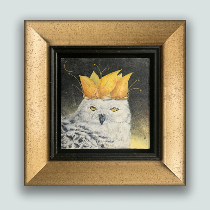 "Autumn Coronation" painting by Diane Savino. A snow owl wears a crown of golden leaves, with a sliver of the moon showing in a dark sky. The artwork is in a mottled gold frame and shown on a pale blue wall.
