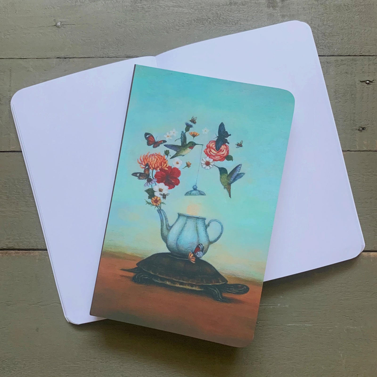 Duy Huynh notebook featuring his artwork "A Matter of Space, Pace and EquanimiTea" artwork. A turtle carries a teapot on its back. Flowers bloom from the teapot, with butterflies and hummingbirds fluttering around. 