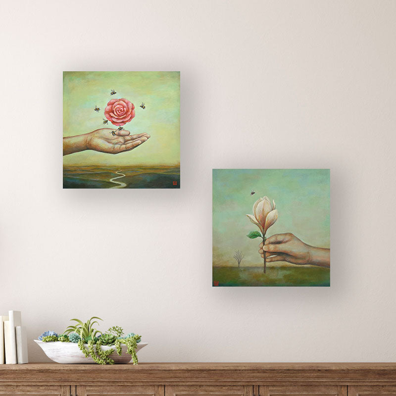 Two 12 x 12" paintings by Charlotte NC artist Duy Huynh. In each painting a hand reaches out in front of open landscapes, holding a single flower.