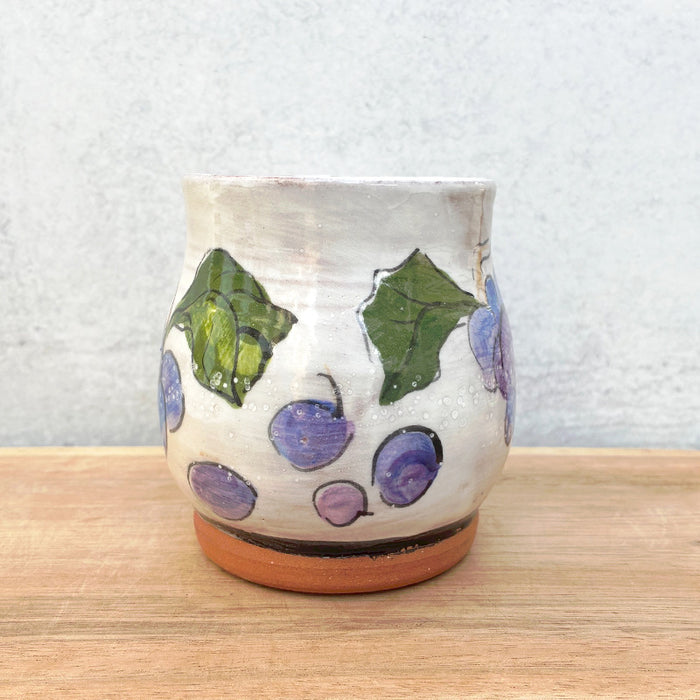 Handmade ceramic mug by NC potter Molly Lithgo. White with purple grape and green leaf decoration. View 2.