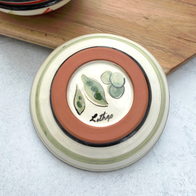 Handmade ceramic bowl with green peas in pods decoration on the interior by artist Molly Lithgo.  Bottom view with stripes and green peas on base. 