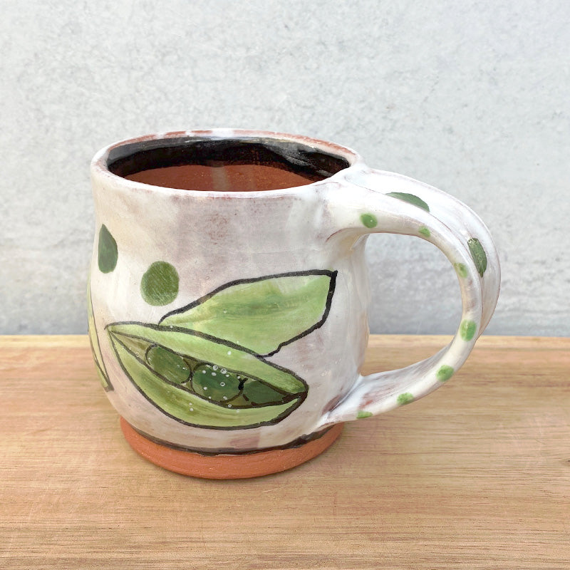 Handmade ceramic mug by NC potter Molly Lithgo. White with green pea pods decoration. View with handle detail.