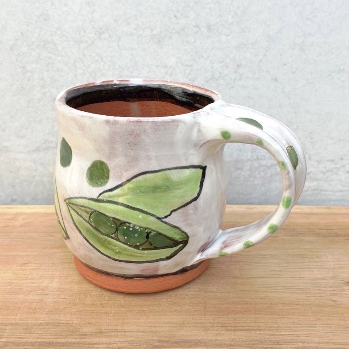 Handmade ceramic mug by NC potter Molly Lithgo. White with green pea pods decoration. View with handle detail.