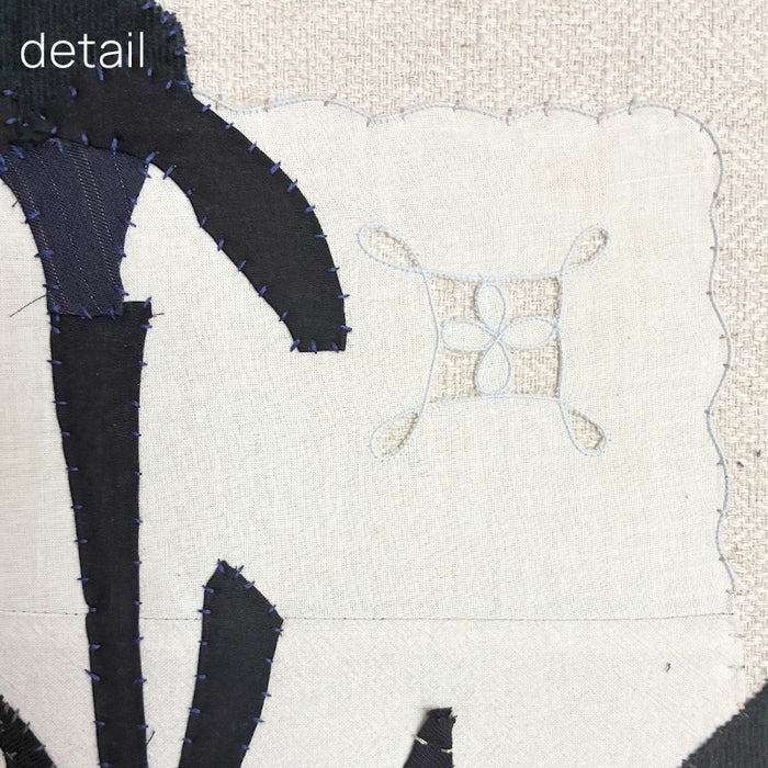 Framed textile artwork of black iris flowers on a textured beige background by Hannah Goff. Detail shown. 