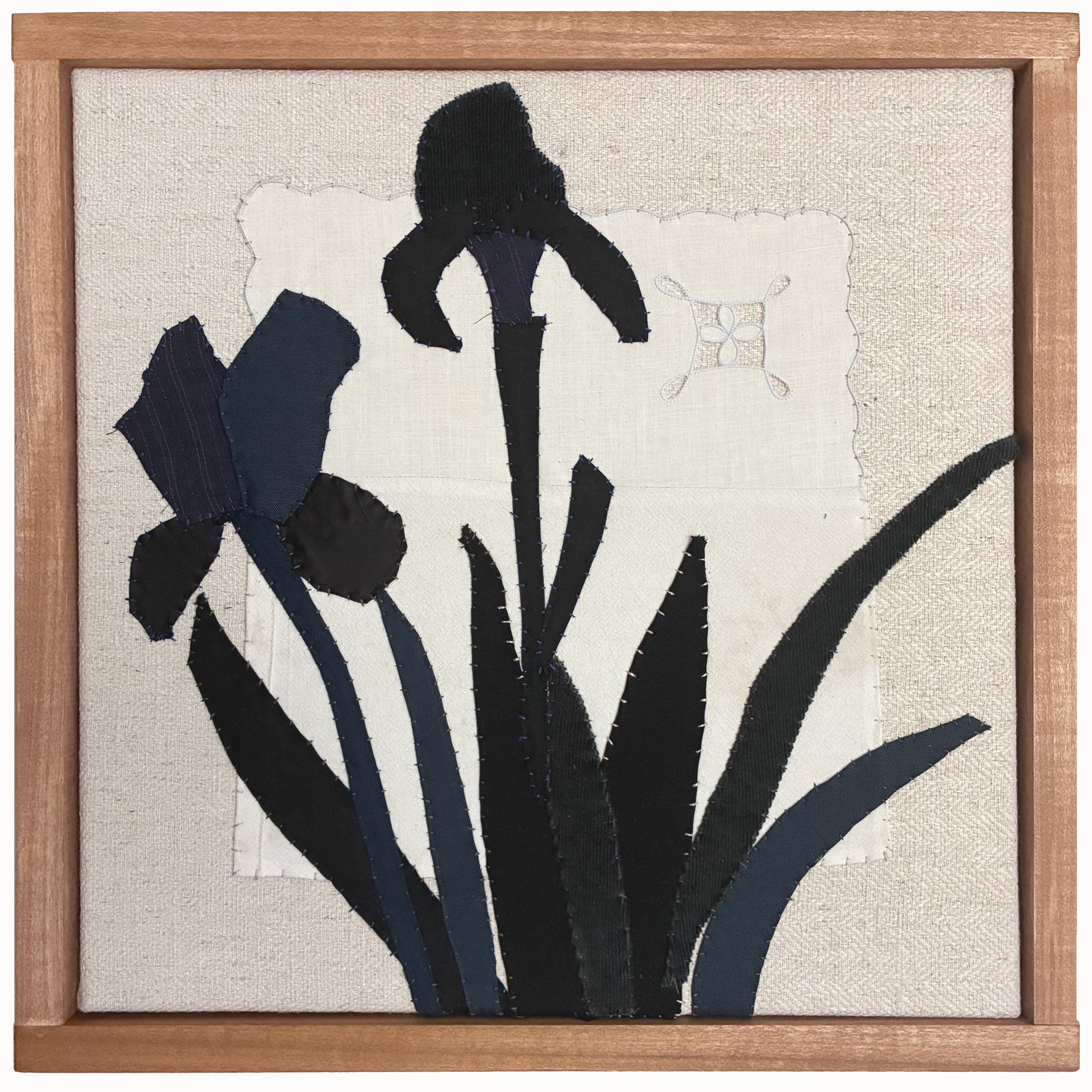 Framed textile artwork of black iris flowers on a textured beige background by Hannah Goff. 