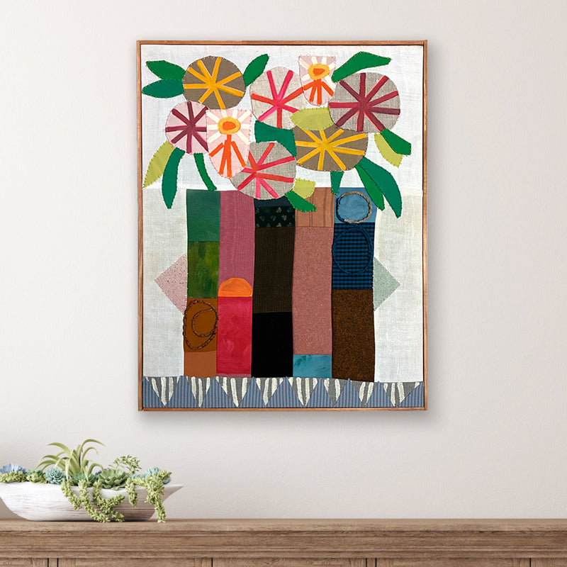 Artwork by Hannah Goff. Mixed media textile painting with geometric vase and colorful abstracted flowers displayed on wall. 