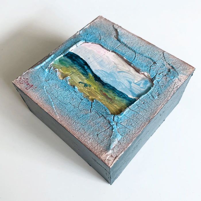 Ancient View, a small mixed media painting by artist Hannah Seng. View of a mini landscape in blues and greens set inside a window of thick, textured paint. View 2.