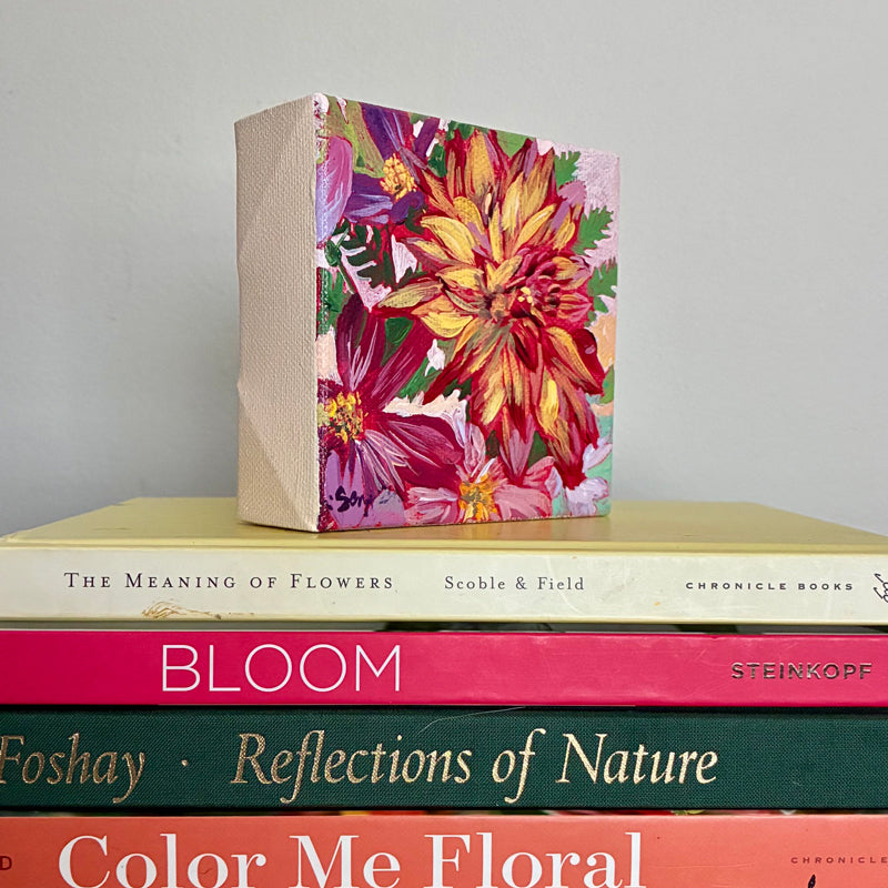 Mini painting of dahlias by Hannah Seng, sitting on a stack of flower themed books.
