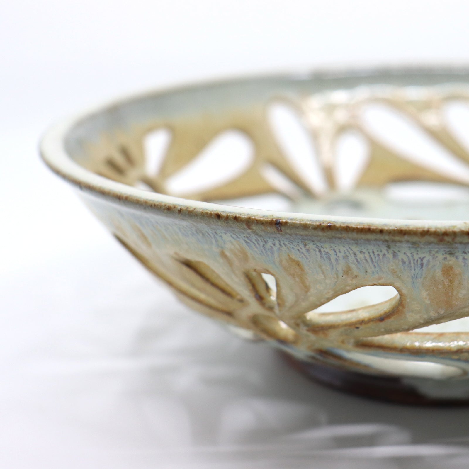 Detail of handmade, wood-fired bowl with flower pattern cut-outs, by Heather Ossandon.