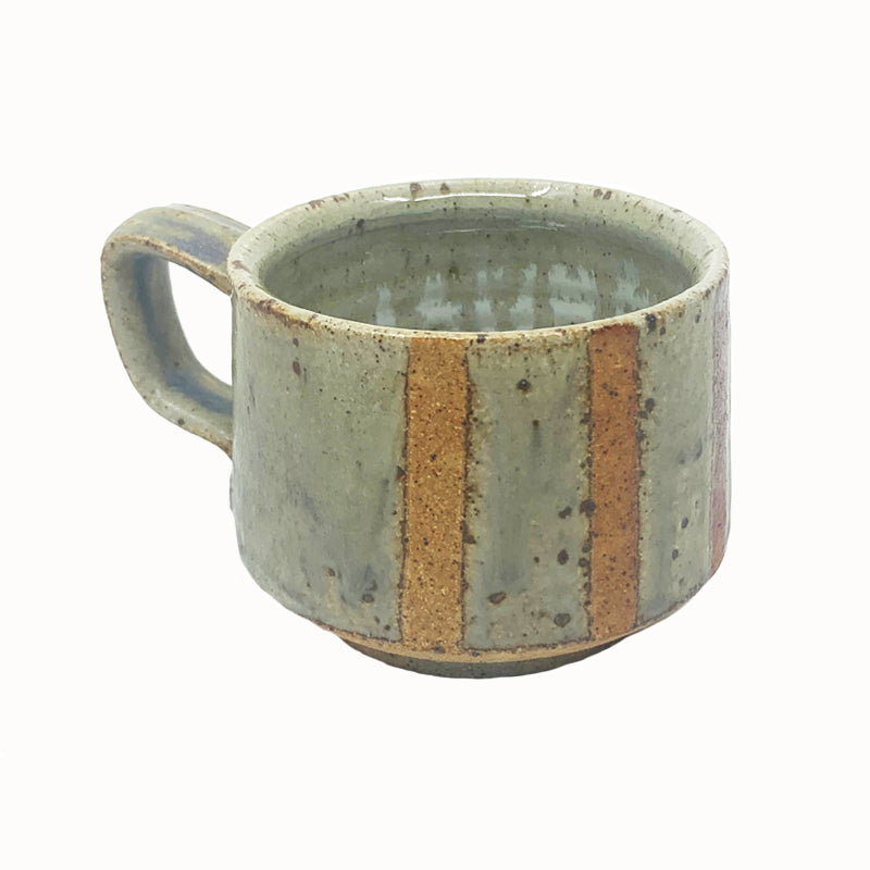 Heather Ossandon handmade, woodfired mug, angled view. Light green with rusty stripes.