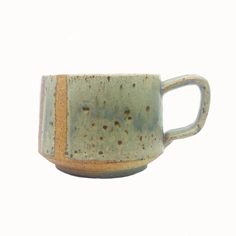 Heather Ossandon handmade, woodfired mug, angled view. Light green with rusty stripes.