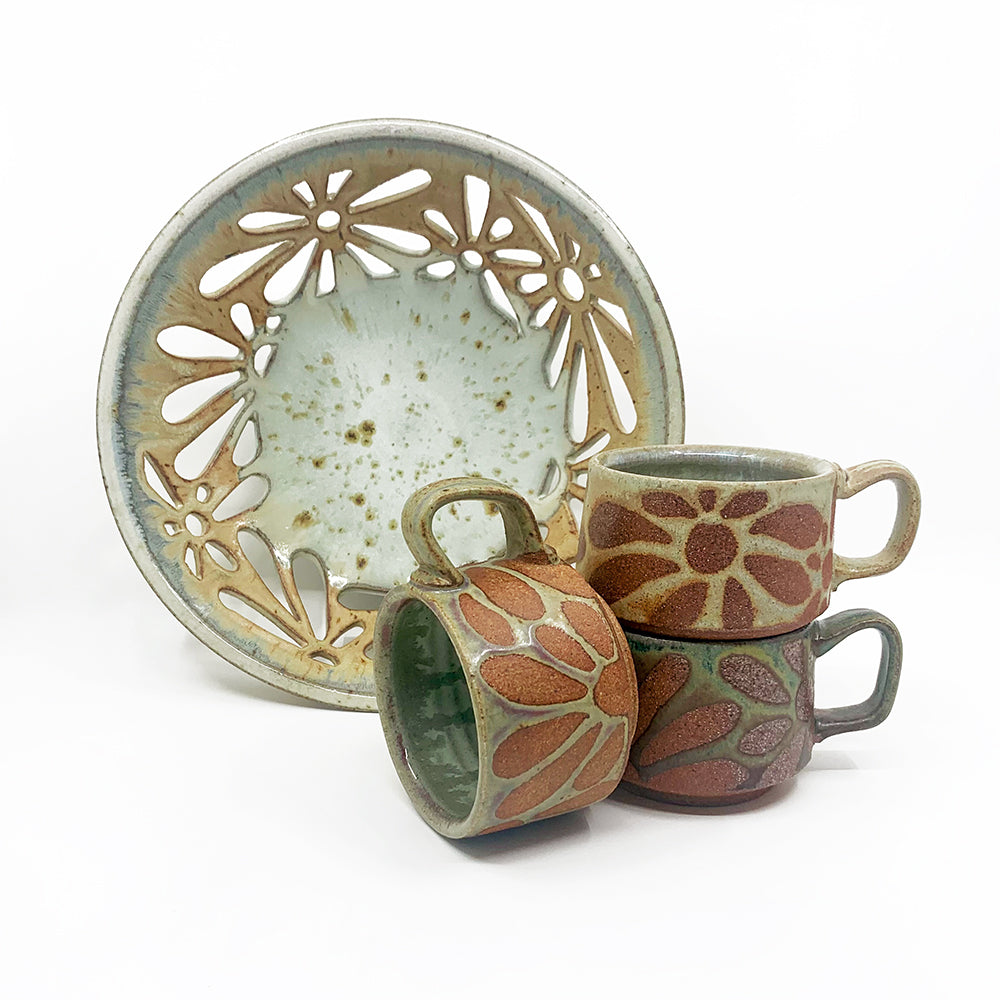 Wood-fired ceramics by Heather Ossandon - Fruit bowl with flower cutouts and mugs with wax resit flower patterns.