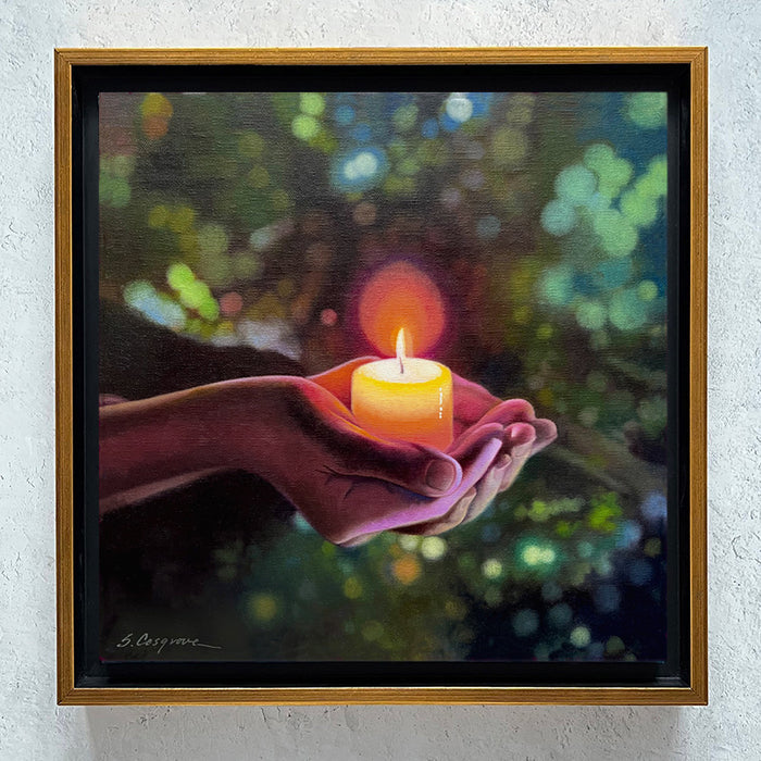 Framed painting by Sharon Cosgrove of a hand holding a lit candle against a blurred natural background in greens and blues. Artwork shown hanging on wall.