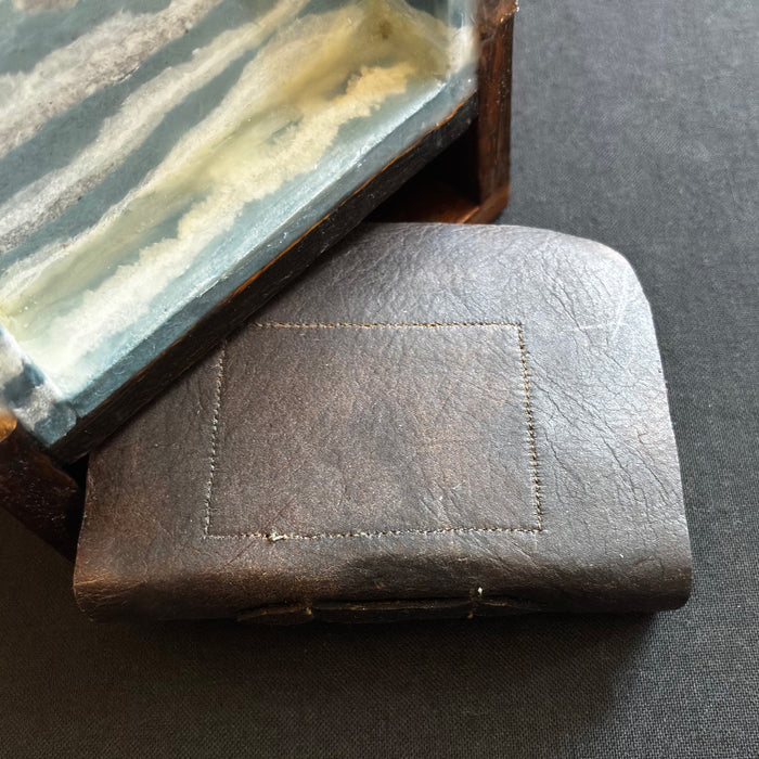 Tall, narrow box with finial on top, mixed media encaustic artwork encased inside, and a small handmade book. Artwork by Janet Eskridge. Close up of leather book cover. 