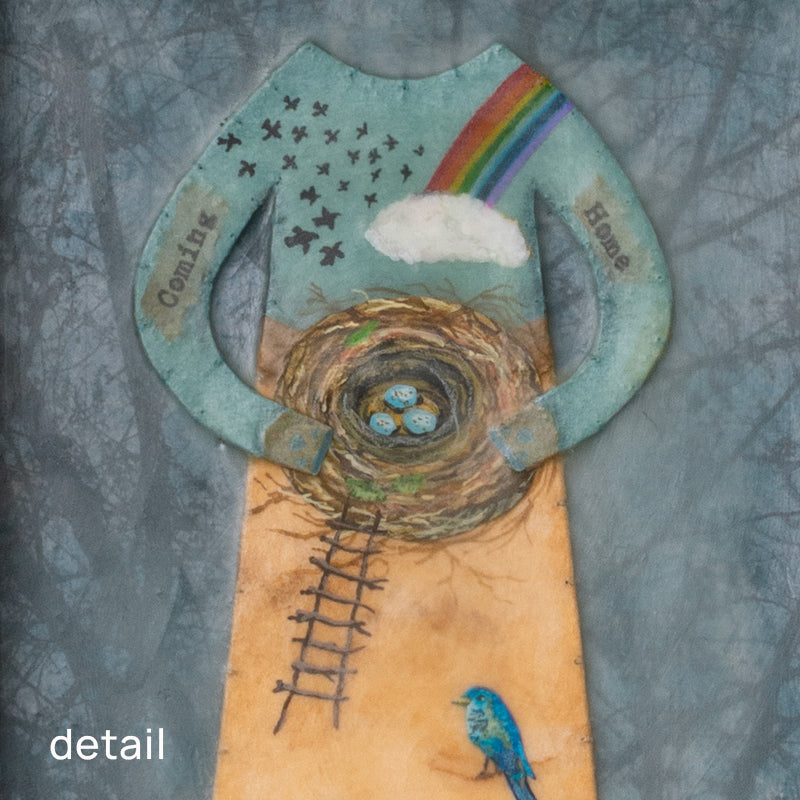 "Homecoming" mixed media assemblage by Janet Eskridge. A figure  in dress holds a bird's next. The dress is decorated with a rainbow, and various birds. The artwork is set inside a vintage wood box with a finial on top. Detail of nest area shown.