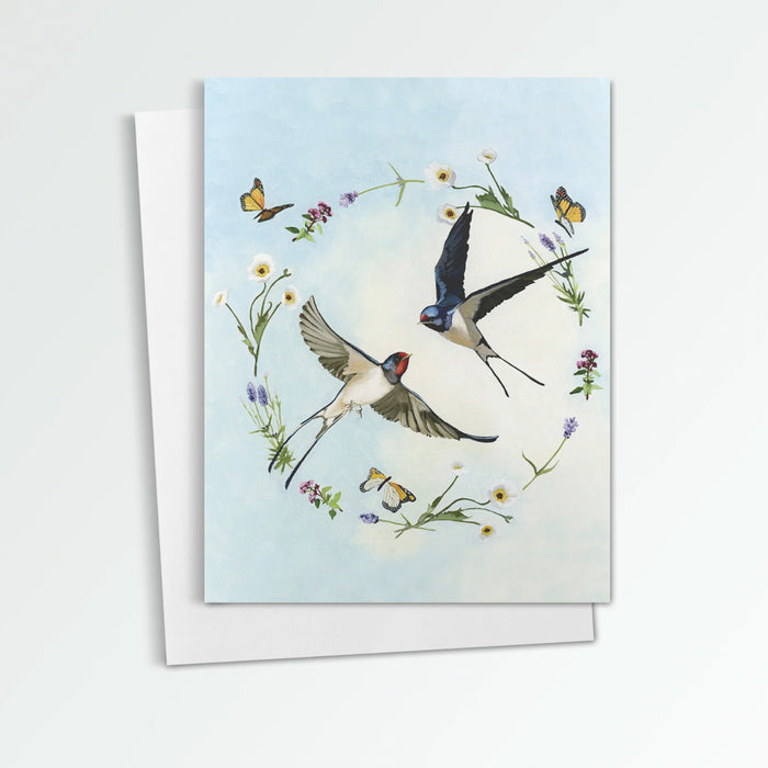 Spring Swallows notecard from Kim Ferreira. Two swallows fly in the sky, a ring of flowers and butterflies around them.