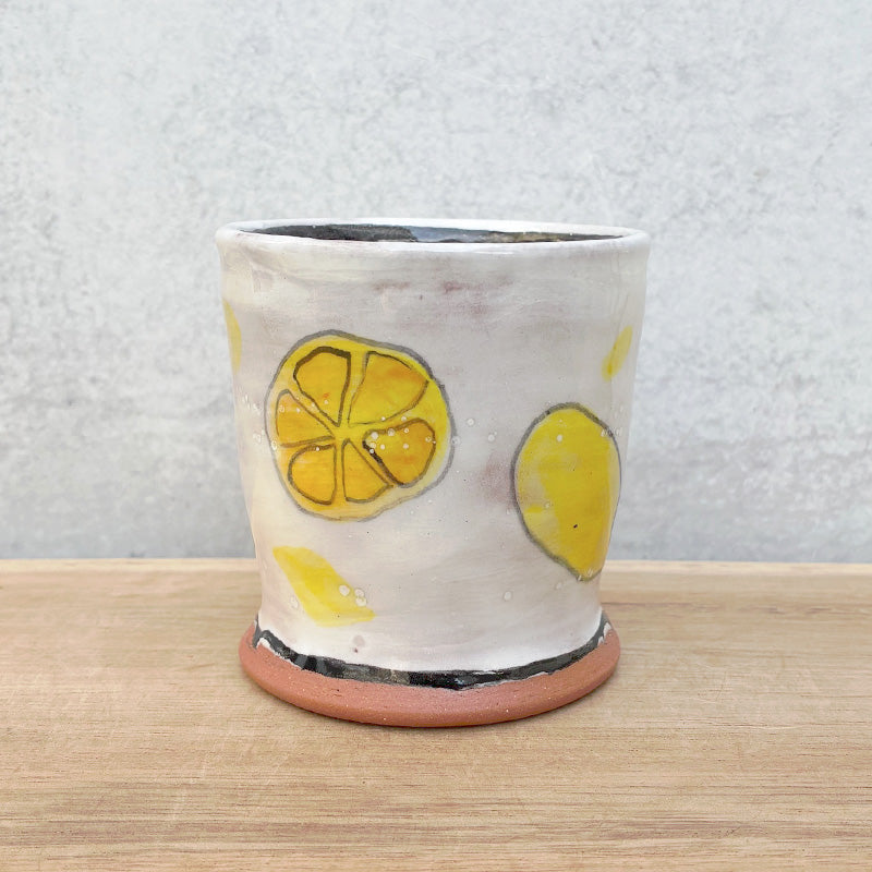 Small handmade cup by Molly Lithgo. White with lemons and lemon slices. 