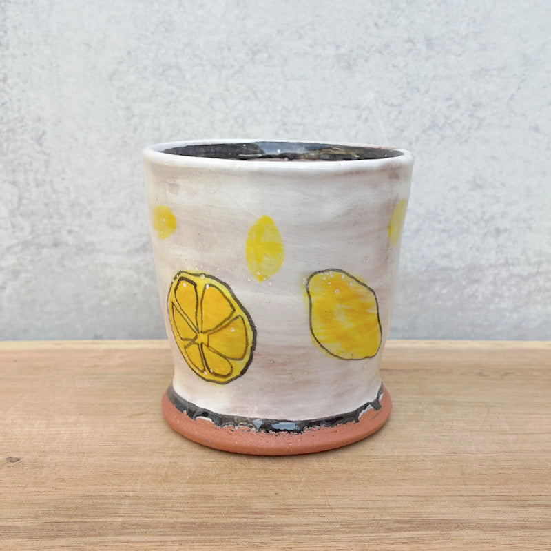 Small handmade cup by Molly Lithgo. White with lemons and lemon slices. Alternate view.