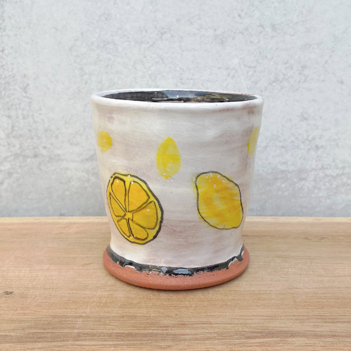 Small handmade cup by Molly Lithgo. White with lemons and lemon slices. Alternate view.