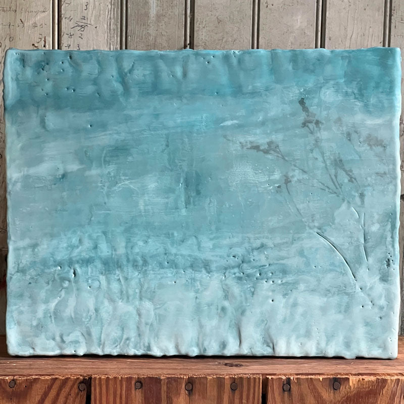 Mixed media encaustic painting by Liberty Hanson Wild in soft blues with botanical detail. Displayed against a wood backdrop. 