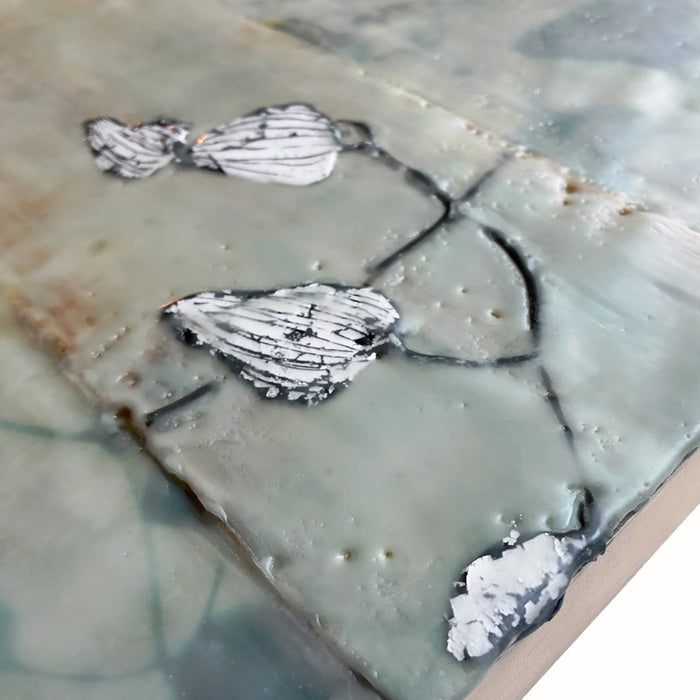 Mixed media encaustic artwork on panel, soft neutral tones in grid pattern with leaves and silver detail. Close up detail. 