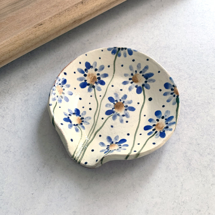 Handmade ceramic spoon rest by Molly Lithgo, decorated with blue and golden flowers. Made in North Carolina.