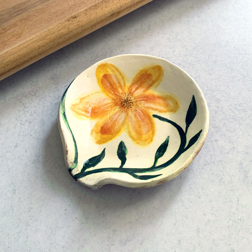 Handmade ceramic spoon rest by Molly Lithgo, decorated a golden yellow flower. Made in North Carolina.