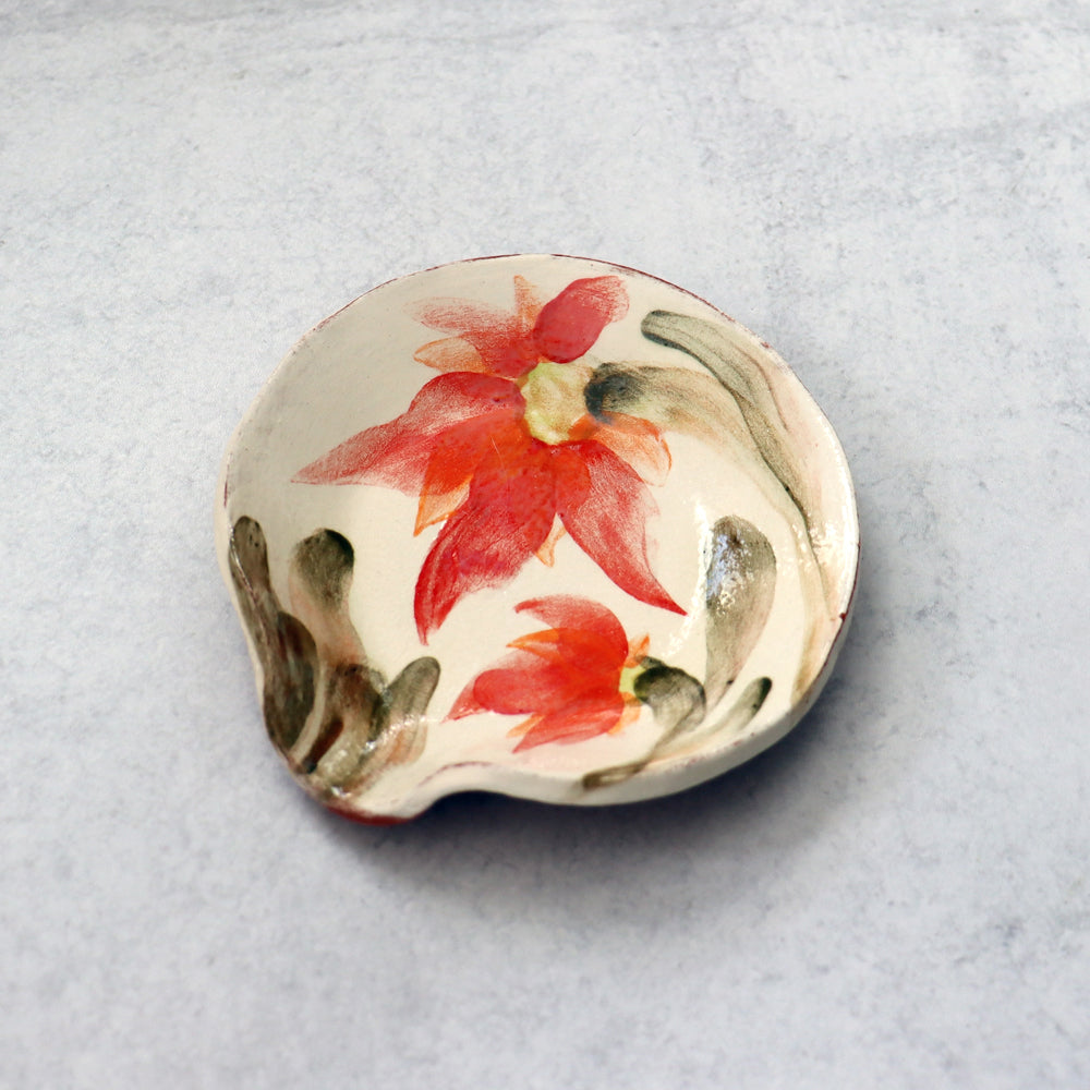 Handmade ceramic spoon rest by Molly Lithgo, decorated with bright red flowers.